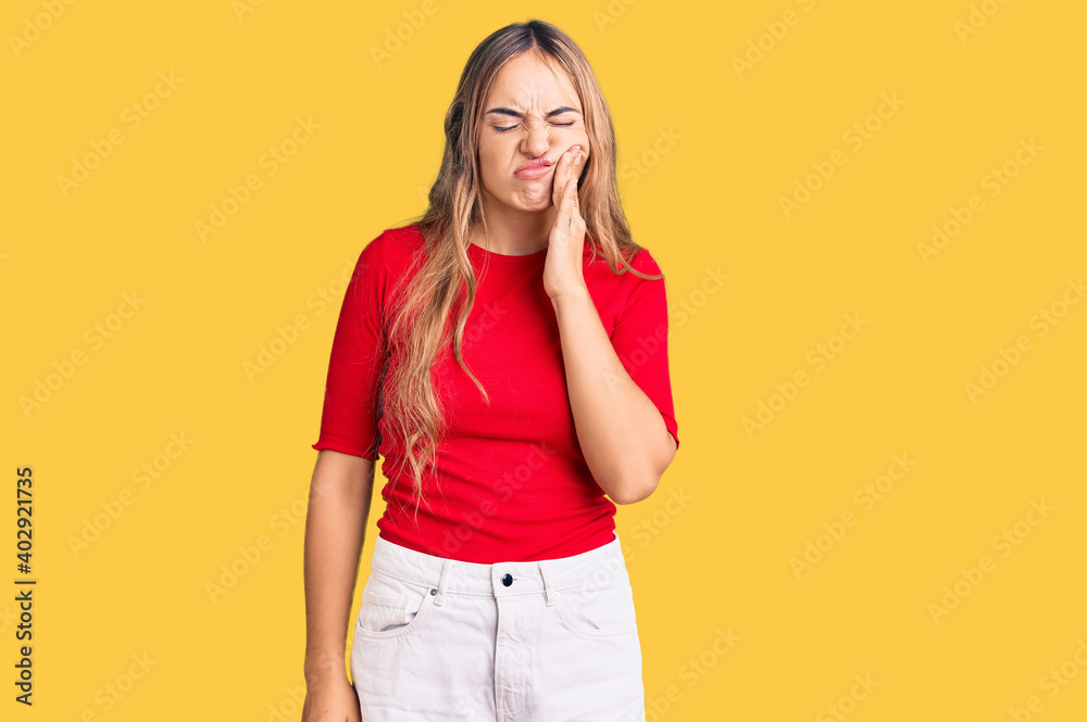 Young beautiful blonde woman wearing casual clothes touching mouth with hand with painful expression because of toothache or dental illness on teeth. dentist Young beautiful blonde woman wearing casual clothes touching mouth with hand with painful expression because of toothache or dental illness on teeth. dentist