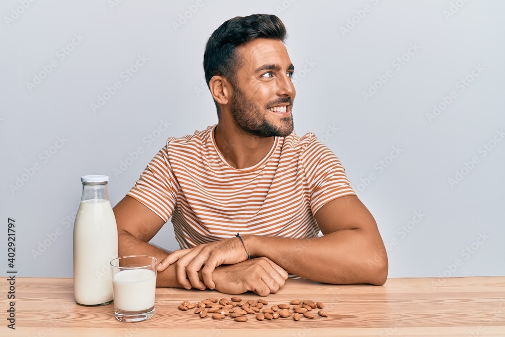 Handsome hispanic man drinking healthy almond milk looking to side, relax profile pose with natural face and confident smile. Handsome hispanic man drinking healthy almond milk looking to side, relax profile pose with natural face and confident smile.