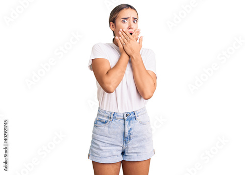 Young beautiful blonde woman wearing casual white tshirt shocked covering mouth with hands for mistake. secret concept. photo