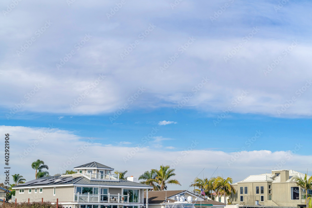 Fototapeta Picturesque skyscape of blue sky and clouds over beautiful waterfront houses