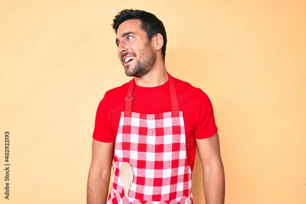 Young hispanic man wearing professional baker apron looking to side, relax profile pose with natural face and confident smile.