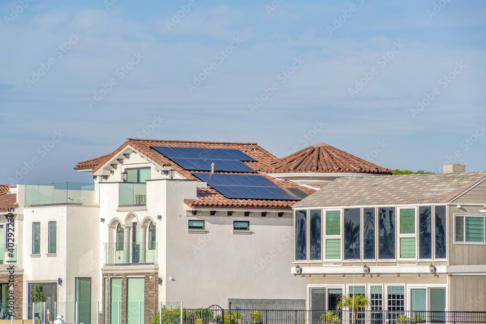House with white exterior wall and solar panels on tile roof in Huntington Beach