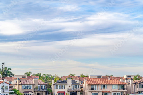 Houses and palm trees against a cloudy skyscape in Huntington Beach California