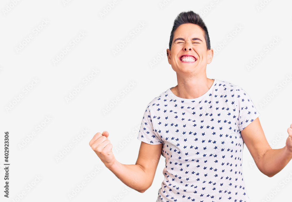 Young woman with short hair wearing casual clothes very happy and excited doing winner gesture with arms raised, smiling and screaming for success. celebration concept. Young woman with short hair wearing casual clothes very happy and excited doing winner gesture with arms raised, smiling and screaming for success. celebration concept.