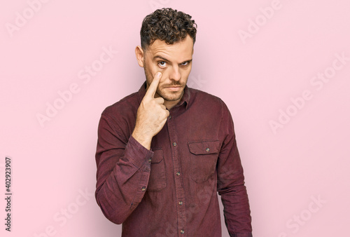 Young hispanic man wearing casual clothes pointing to the eye watching you gesture, suspicious expression © Krakenimages.com