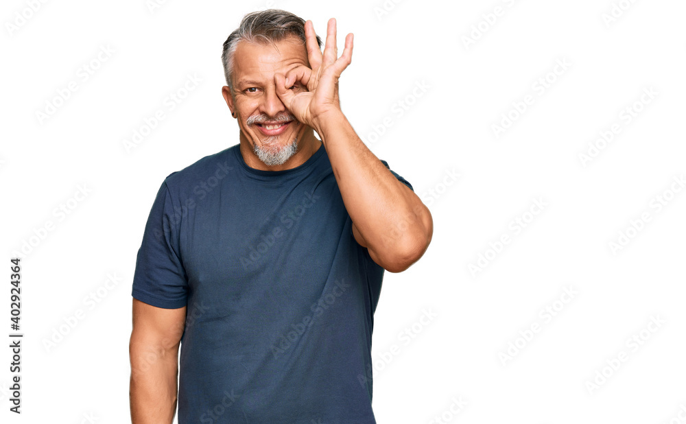Middle age grey-haired man wearing casual clothes doing ok gesture with hand smiling, eye looking through fingers with happy face. Middle age grey-haired man wearing casual clothes doing ok gesture with hand smiling, eye looking through fingers with happy face.