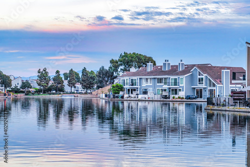 Bayfront houses overlooking the calm sea that reflects the cloudy sky at sunset
