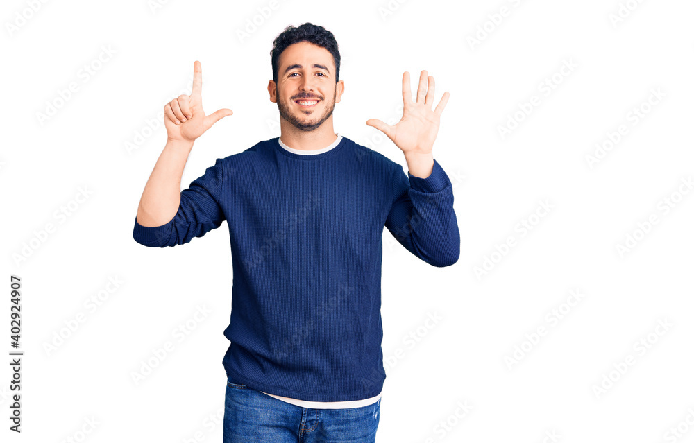 Young hispanic man wearing casual clothes showing and pointing up with fingers number seven while smiling confident and happy. Young hispanic man wearing casual clothes showing and pointing up with fingers number seven while smiling confident and happy.