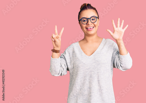 Young latin woman wearing casual clothes showing and pointing up with fingers number seven while smiling confident and happy.