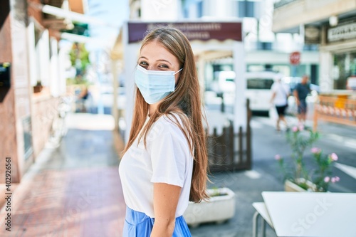Young caucasian woman wearing coronavirus protection medical mask walking at the city
