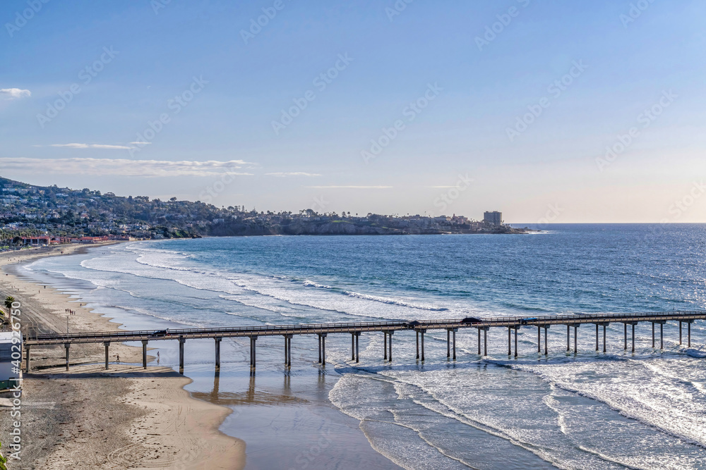 Pier over sandy beach and blue ocean with view of sky in San Diego California