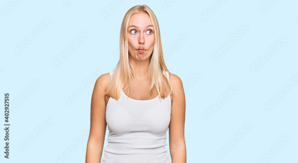 Young blonde girl wearing casual style with sleeveless shirt making fish face with lips, crazy and comical gesture. funny expression. Young blonde girl wearing casual style with sleeveless shirt making fish face with lips, crazy and comical gesture. funny expression.