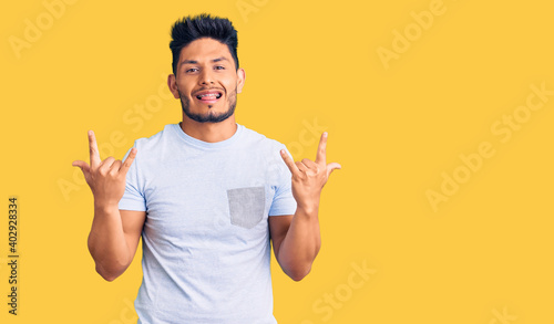 Handsome latin american young man wearing casual clothes shouting with crazy expression doing rock symbol with hands up. music star. heavy concept.