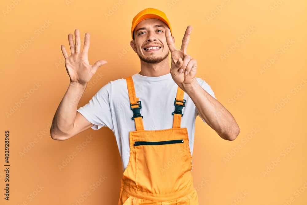 Hispanic young man wearing handyman uniform showing and pointing up with fingers number seven while smiling confident and happy. Hispanic young man wearing handyman uniform showing and pointing up with fingers number seven while smiling confident and happy.