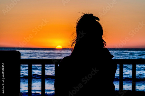 Silhouette of woman at ocean watching the golden sunset in San Diego California photo