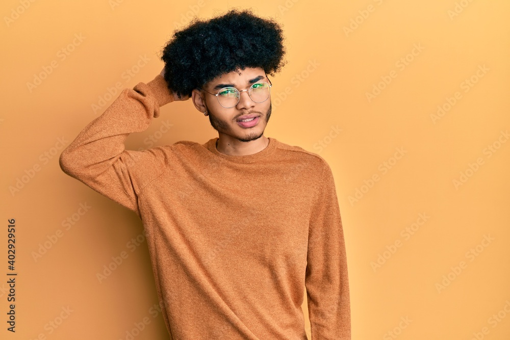 Young african american man with afro hair wearing casual winter sweater confuse and wonder about question. uncertain with doubt, thinking with hand on head. pensive concept. Young african american man with afro hair wearing casual winter sweater confuse and wonder about question. uncertain with doubt, thinking with hand on head. pensive concept.