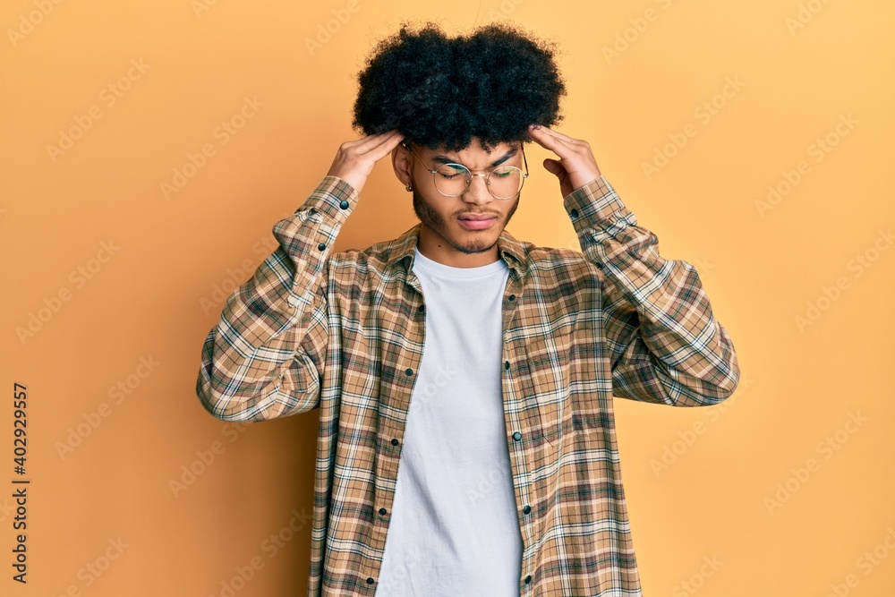 Young african american man with afro hair wearing casual clothes with hand on head, headache because stress. suffering migraine. Young african american man with afro hair wearing casual clothes with hand on head, headache because stress. suffering migraine.