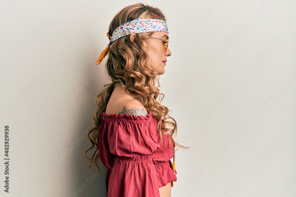 Young blonde girl wearing bohemian and hippie style looking to side, relax profile pose with natural face with confident smile. Young blonde girl wearing bohemian and hippie style looking to side, relax profile pose with natural face with confident smile.