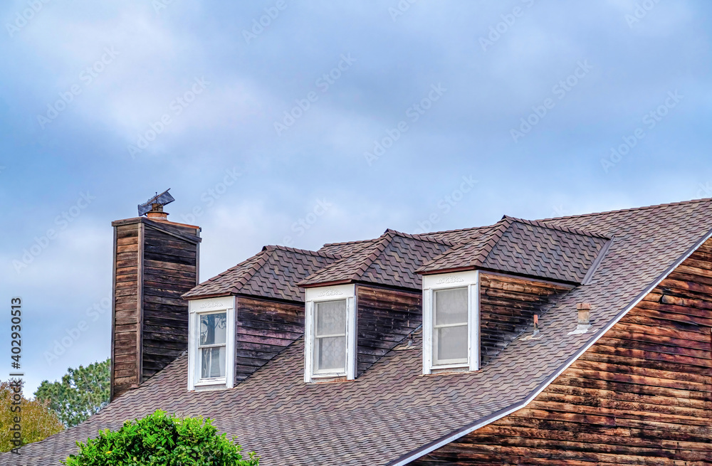 Dormer windows on gray roof of house with chimney in San Diego California