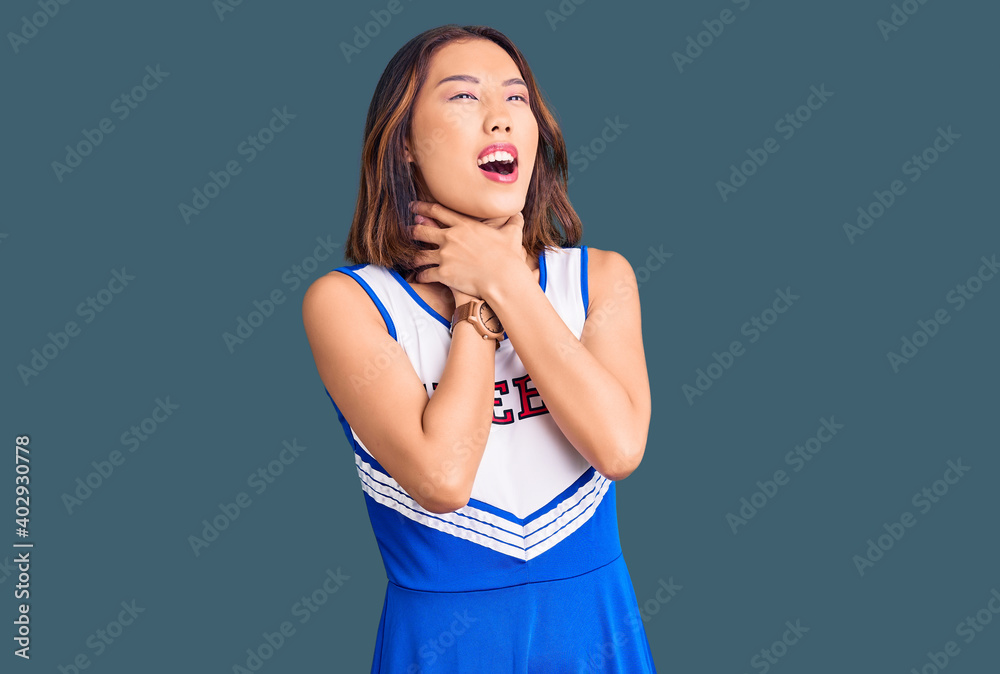Young beautiful chinese girl wearing cheerleader uniform shouting suffocate because painful strangle. health problem. asphyxiate and suicide concept. Young beautiful chinese girl wearing cheerleader uniform shouting suffocate because painful strangle. health problem. asphyxiate and suicide concept.