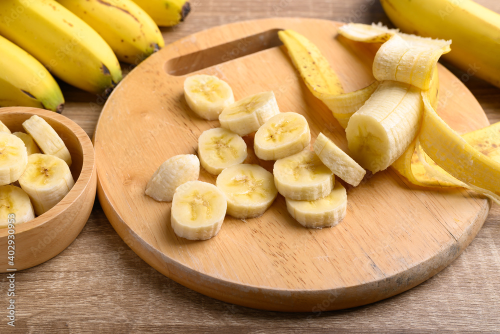 Sliced ripe banana fruit on wooden cutting board preparing for cooking Sliced ripe banana fruit on wooden cutting board preparing for cooking