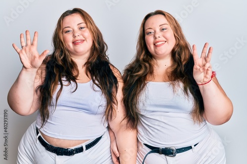 Plus size caucasian sisters woman wearing casual white clothes showing and pointing up with fingers number eight while smiling confident and happy.