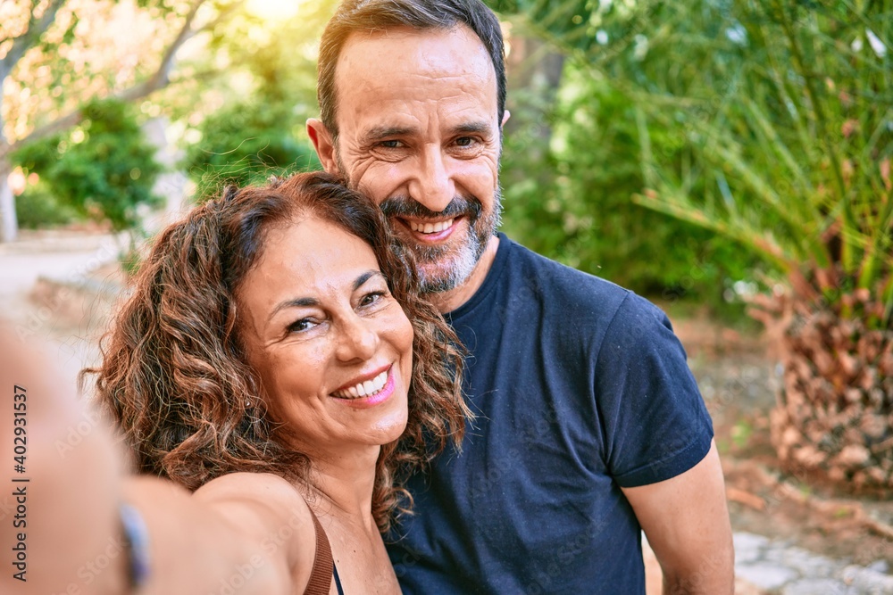 Middle age couple wearing casual clothes smiling happy making selfie by the camera at the forest Middle age couple wearing casual clothes smiling happy making selfie by the camera at the forest