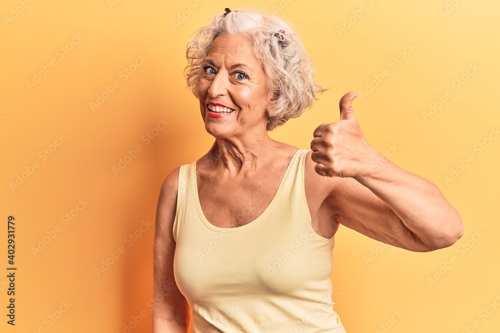 Senior grey-haired woman wearing casual clothes doing happy thumbs up gesture with hand. approving expression looking at the camera showing success. Senior grey-haired woman wearing casual clothes doing happy thumbs up gesture with hand. approving expression looking at the camera showing success.
