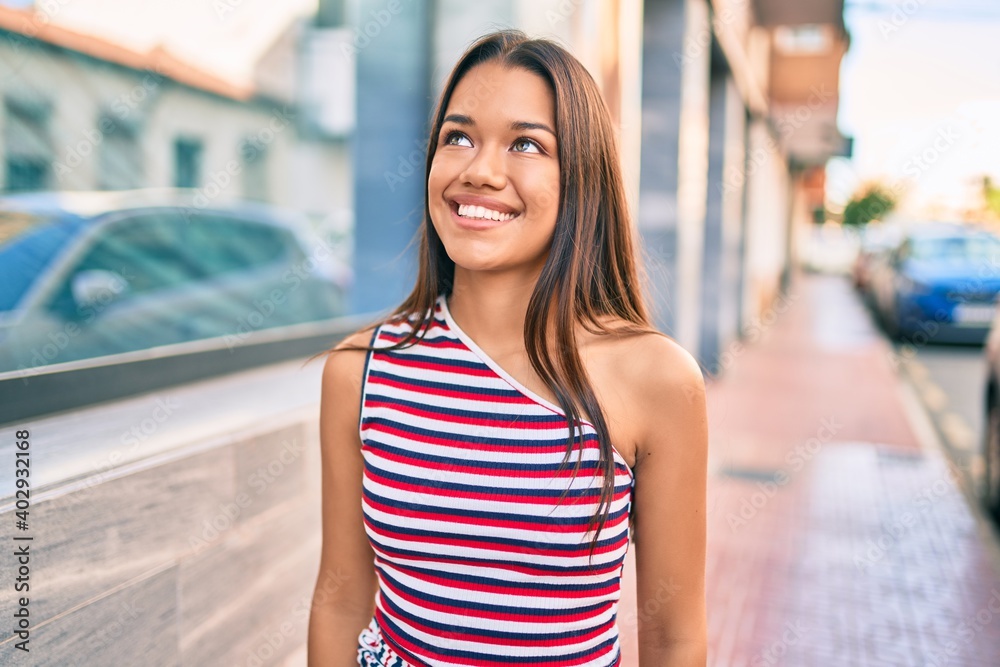 Young latin girl smiling happy walking at the city.