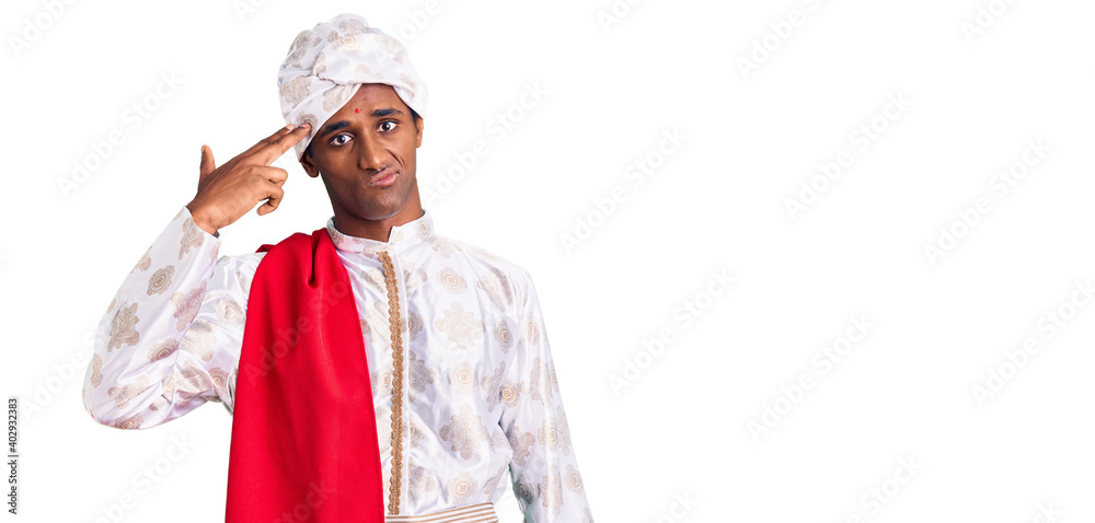 African handsome man wearing tradition sherwani saree clothes shooting and killing oneself pointing hand and fingers to head like gun, suicide gesture. African handsome man wearing tradition sherwani saree clothes shooting and killing oneself pointing hand and fingers to head like gun, suicide gesture.