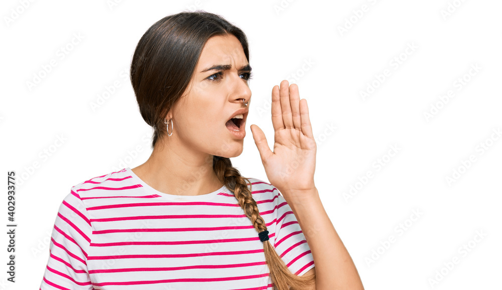 Young hispanic woman wearing casual clothes shouting and screaming loud to side with hand on mouth. communication concept. Young hispanic woman wearing casual clothes shouting and screaming loud to side with hand on mouth. communication concept.