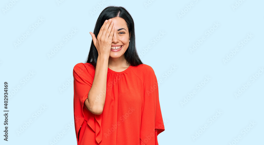 Beautiful young woman wearing casual clothes covering one eye with hand, confident smile on face and surprise emotion. Beautiful young woman wearing casual clothes covering one eye with hand, confident smile on face and surprise emotion.