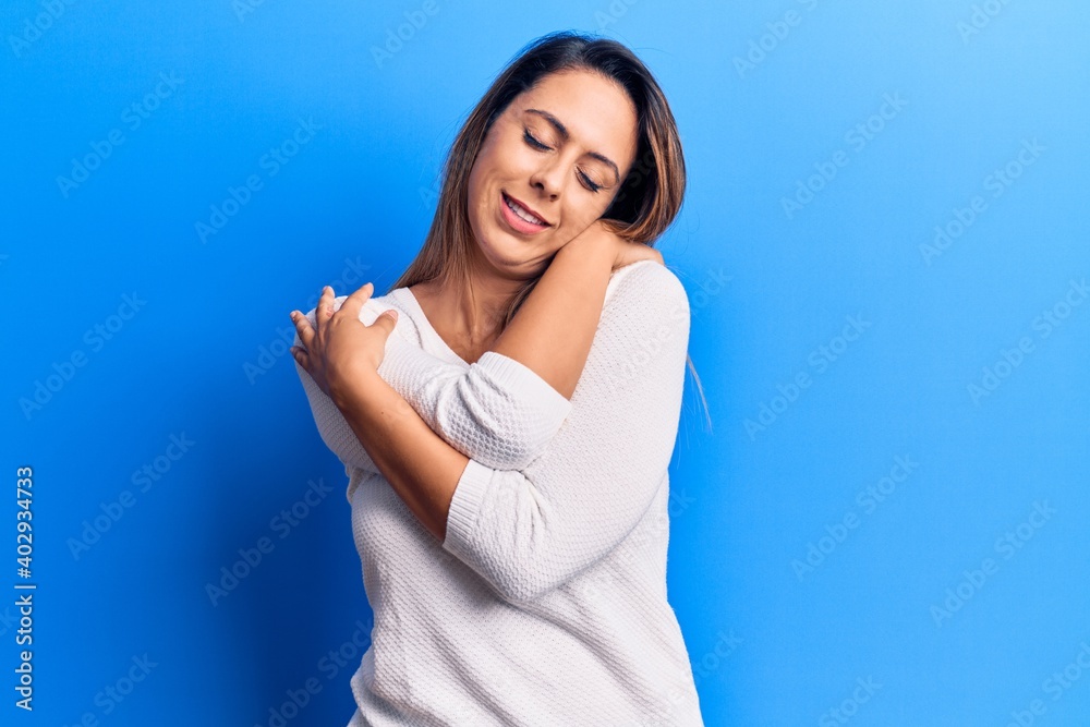 Young beautiful woman wearing casual t shirt hugging oneself happy and positive, smiling confident. self love and self care Young beautiful woman wearing casual t shirt hugging oneself happy and positive, smiling confident. self love and self care