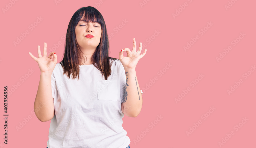 Young plus size woman wearing casual clothes relaxed and smiling with eyes closed doing meditation gesture with fingers. yoga concept.