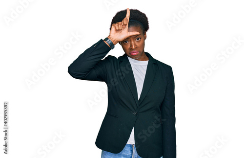 Young african american girl wearing business clothes making fun of people with fingers on forehead doing loser gesture mocking and insulting.