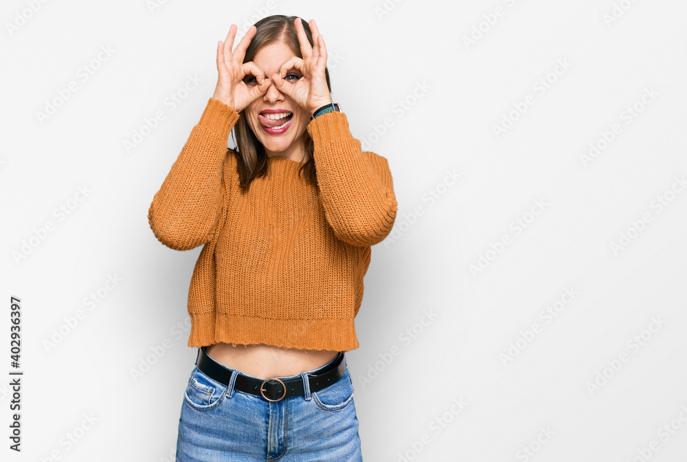 Beautiful caucasian woman wearing casual clothes doing ok gesture like binoculars sticking tongue out, eyes looking through fingers. crazy expression. Beautiful caucasian woman wearing casual clothes doing ok gesture like binoculars sticking tongue out, eyes looking through fingers. crazy expression.