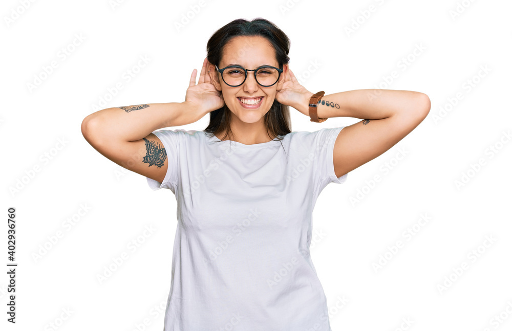 Young hispanic woman wearing casual white t shirt trying to hear both hands on ear gesture, curious for gossip. hearing problem, deaf Young hispanic woman wearing casual white t shirt trying to hear both hands on ear gesture, curious for gossip. hearing problem, deaf