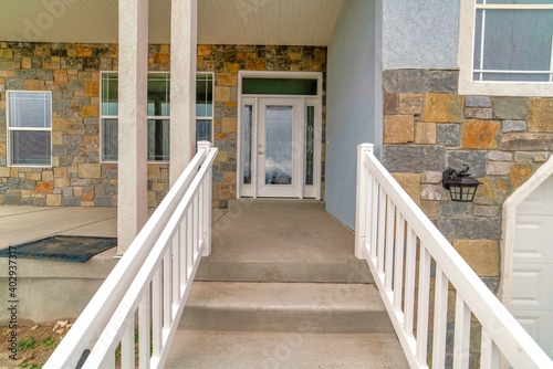 Stairs and porch of home with glass front door sidelights and transom window