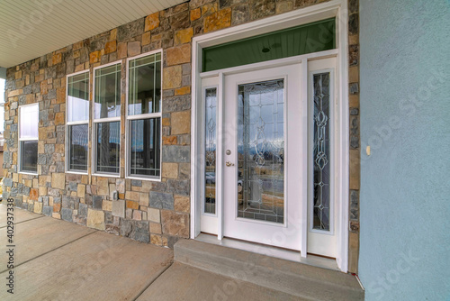 Beautiful glass front door with sidelights and transom window at the home facade