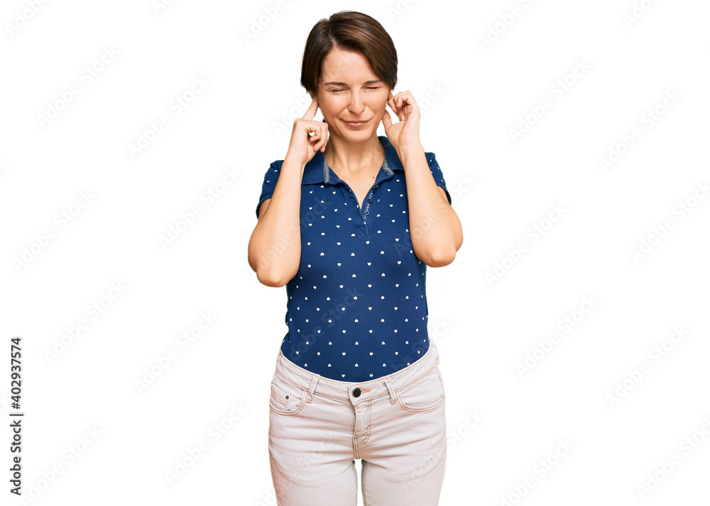 Young brunette woman with short hair wearing casual clothes covering ears with fingers with annoyed expression for the noise of loud music. deaf concept. Young brunette woman with short hair wearing casual clothes covering ears with fingers with annoyed expression for the noise of loud music. deaf concept.