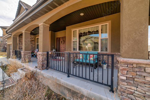 Home facade with spacious open porch featuring arch columns and metal railings