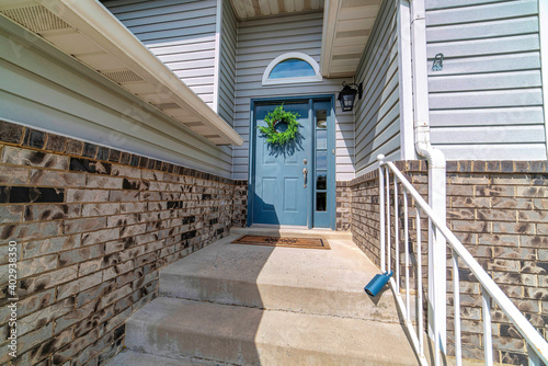 Concrete stairs at home entrance with blue door sidelight and transom window