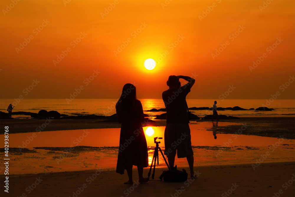Obraz premium Hua Hin, Thailand - October 24, 2020: Man and Women silhouette standing while shootingon a beach in Hua Hin, Thailand.