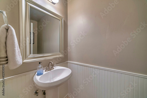 Wall mount sink mirror with white frame and lights inside bathroom of a home