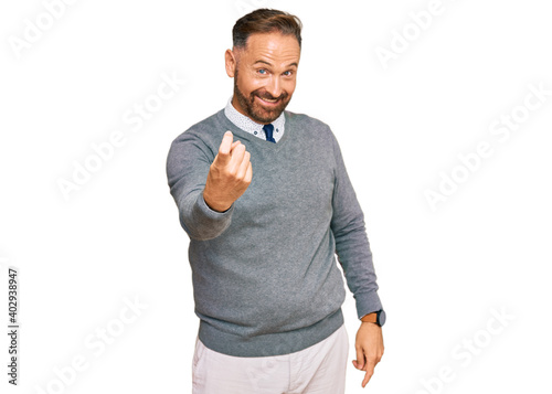 Handsome middle age man wearing business clothes beckoning come here gesture with hand inviting welcoming happy and smiling