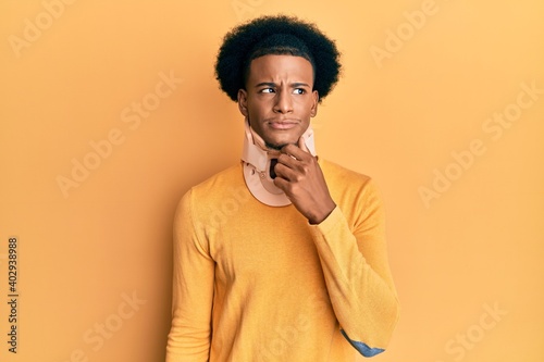 African american man with afro hair wearing cervical neck collar serious face thinking about question with hand on chin, thoughtful about confusing idea © Krakenimages.com