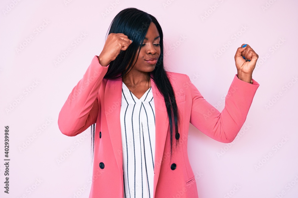Young african american woman wearing business clothes showing arms muscles smiling proud. fitness concept.