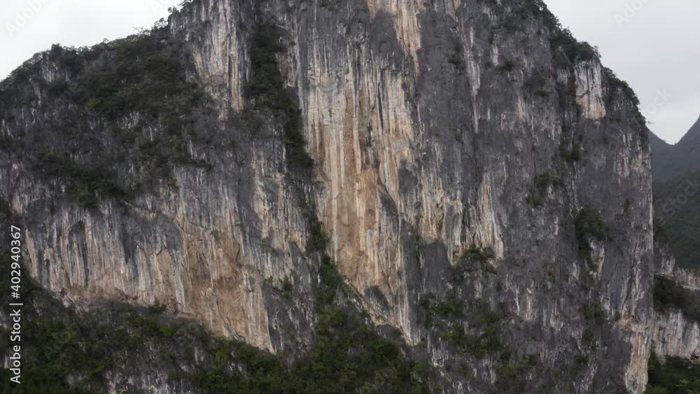Dramatic karst mountain rock face, rugged texture, rising aerial view Dramatic karst mountain rock face, rugged texture, rising aerial view