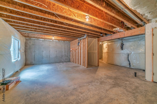 Room under construction with plastic cover on wall and exposed wood beams