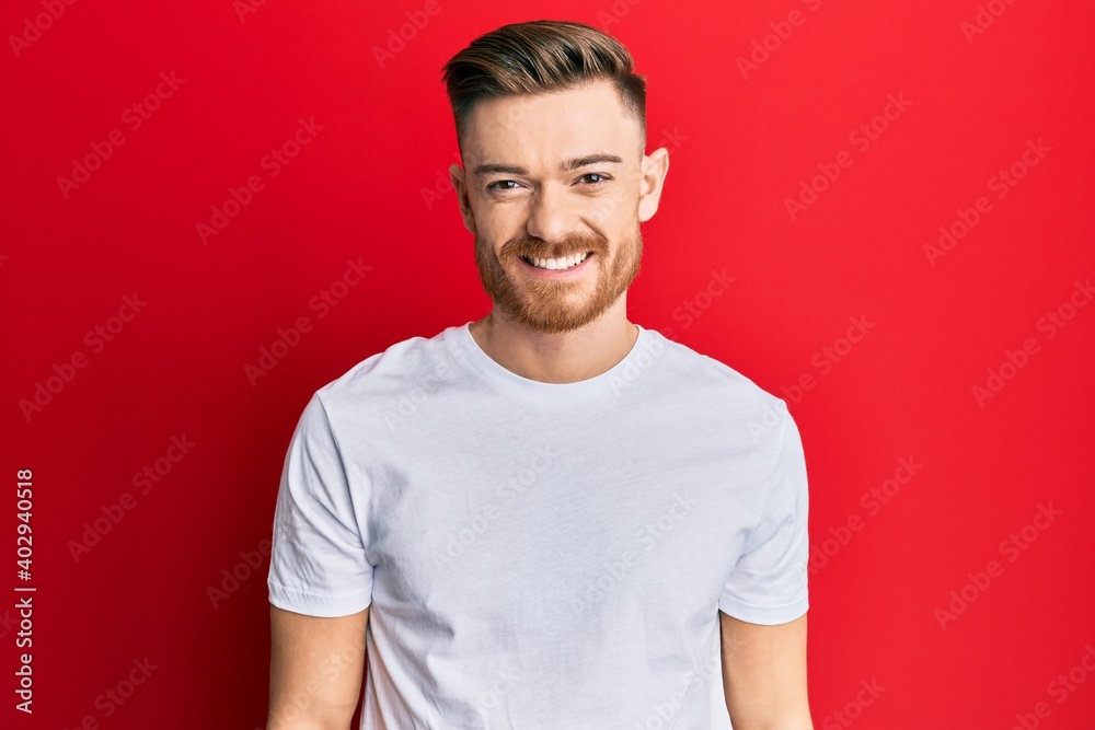 Young redhead man wearing casual white t shirt with a happy and cool smile on face. lucky person. Young redhead man wearing casual white t shirt with a happy and cool smile on face. lucky person.